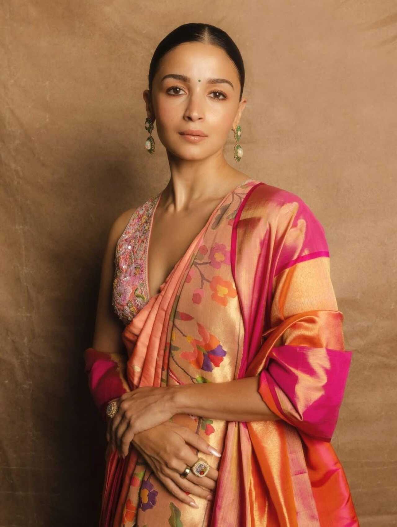 Alia Bhatt brings a fresh, youthful vibe to the Paithani with her peach-toned saree highlighted by a vibrant pink border. The floral patterns add a playful charm, while her sleeveless embroidered blouse enhances the modern silhouette. 